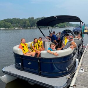 Family of boaters enjoying a Bridge Marina luxury pontoon rental on Lake Hopatcong, NJ.