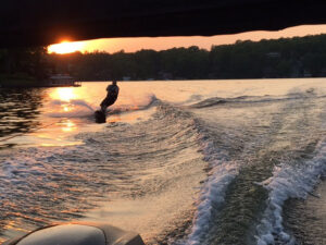 A wakeboard at sunset on Lake Hopatcong being pulled by a Bridge Marina Boat Club bowrider.