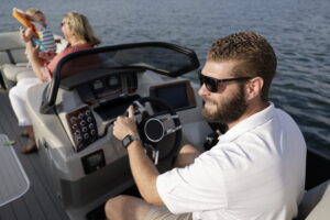 Man drives a Starcraft pontoon boat on Sandy Hook Bay in Highlands from Bridge Marina